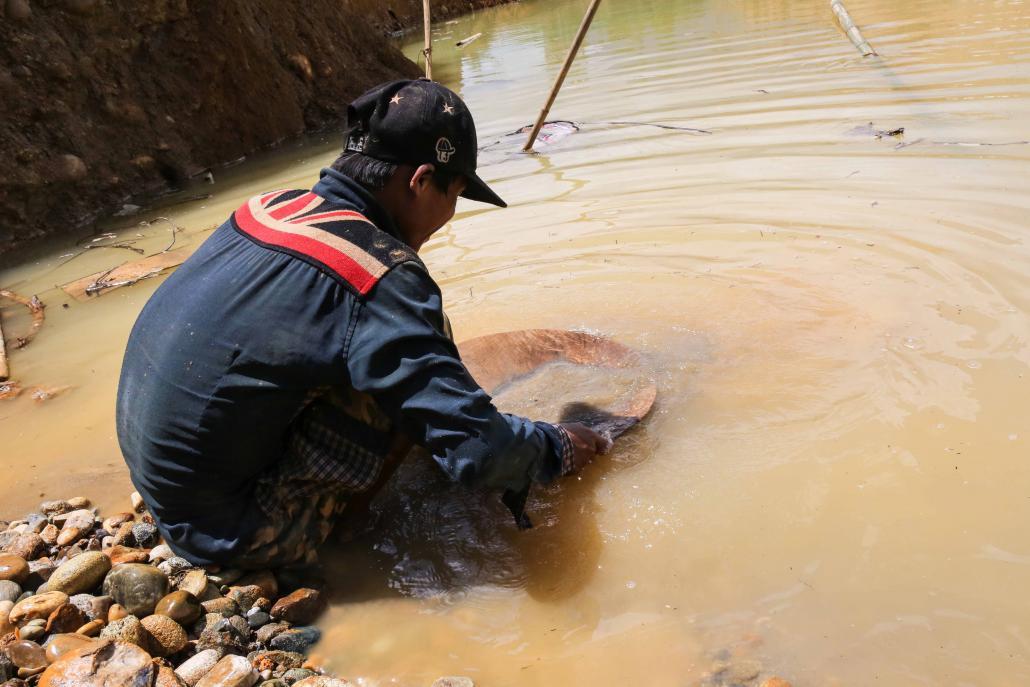 အစိုးရက ပိတ်ပစ်သည့် ရွှေတွင်း၌ ရွှေရှာသူတစ်ဦးက ရွှေမှုန်စုနေစဉ်။ ဓာတ်ပုံ - ဗစ်တိုရီးယား မီလ်ကို