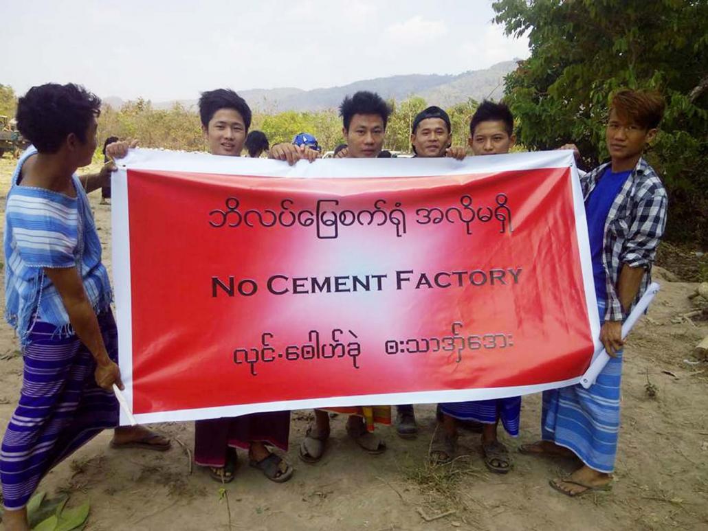 Mi Kayin residents hold a vinyl sign protesting against a proposed cement plant in the area. (KIC)