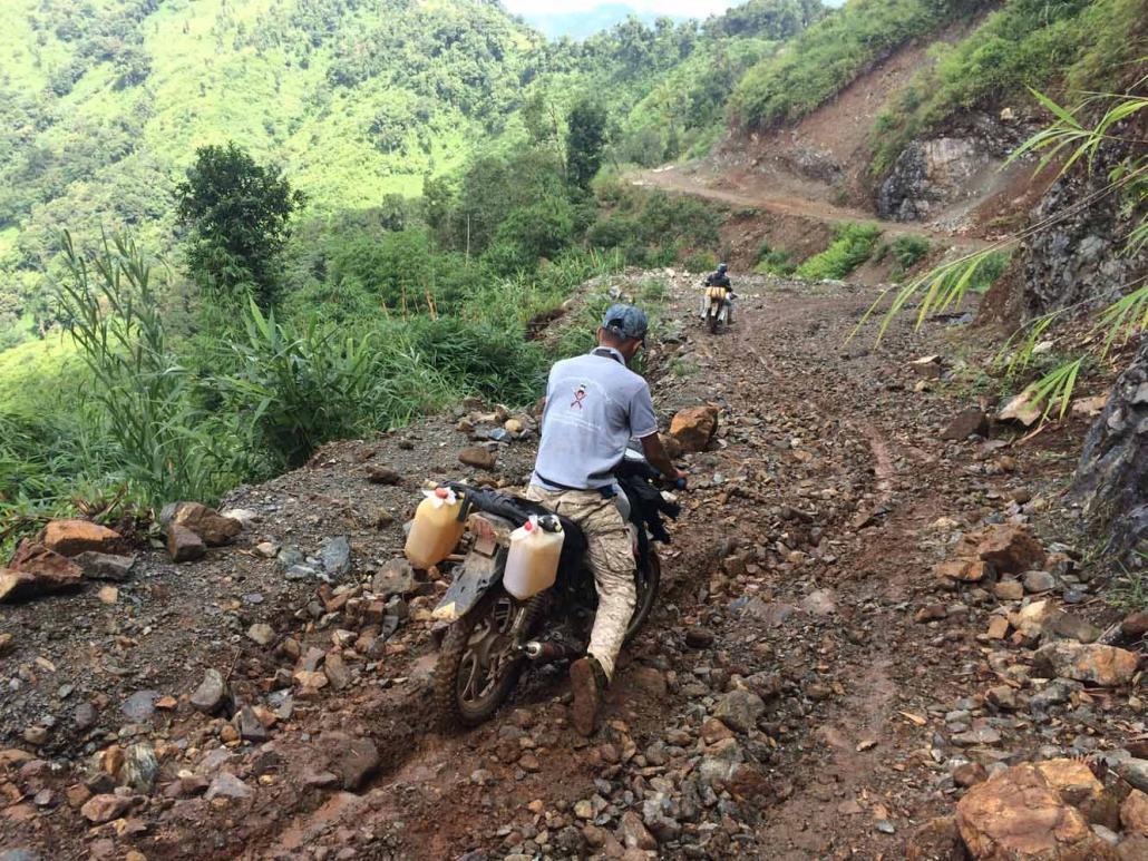 နာဂ ကိုယ်ပိုင်အုပ်ချုပ်ခွင့်ရဒေသရှိ လမ်းကြမ်းတစ်ခုအတိုင်း ခက်ခက်ခဲခဲ ဆိုင်ကယ်စီးနင်းနေသူမျာအား တွေ့ရစဉ်။ ဓာတ်ပုံ - နန်းတင်ထွေး