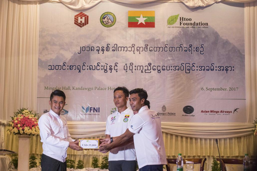 The three climbers accept a US$35,000 donation from Htoo Foundation at a press conference to announce their planned attempt on Hkakabo Razi in Kachin State. (Nyein Su Wai Kyaw Soe | Frontier)