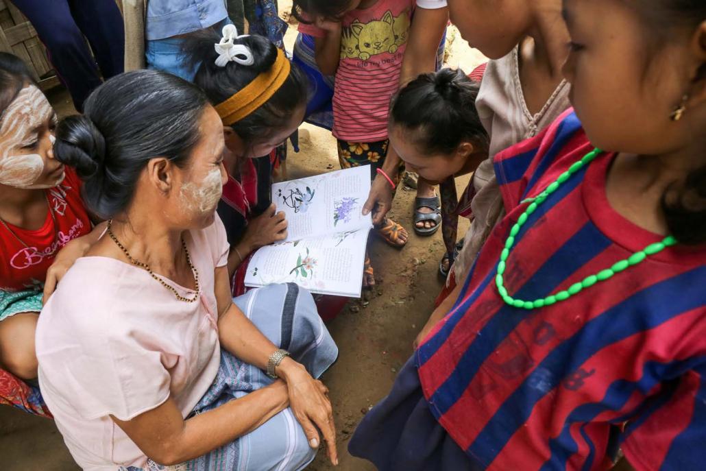 Women read the orchid report at its launch in Ei Htu Hta IDP camp. (Victoria Milko | Frontier)