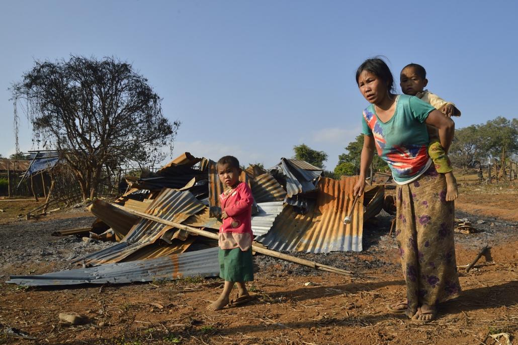 A woman and her two children in the village of Pankan, Kutkai township, in front of their flattened home. (Niels Larsen / Frontier)