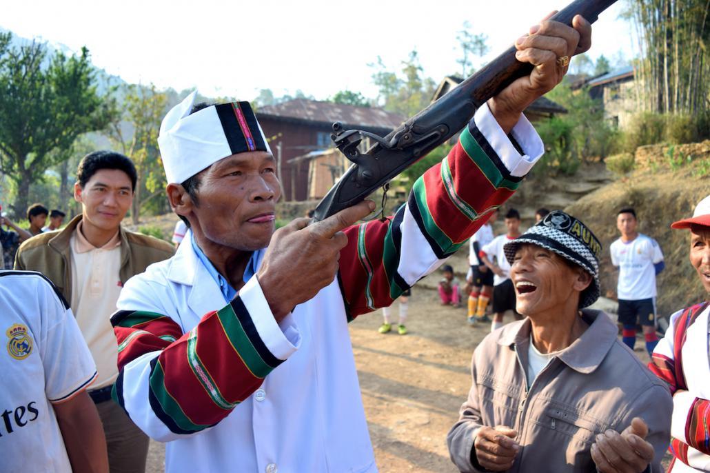 ချင်းရိုးရာ အဝတ်အစားကို ဝတ်ဆင်ထားသော ချင်းအမျိုးသားတစ်ဦးက သေနတ်ဖြင့် ဓာတ်ပုံ အရိုက်ခံနေပုံ။ ဓာတ်ပုံ - ရှားလော့ အင်္ဂလန်