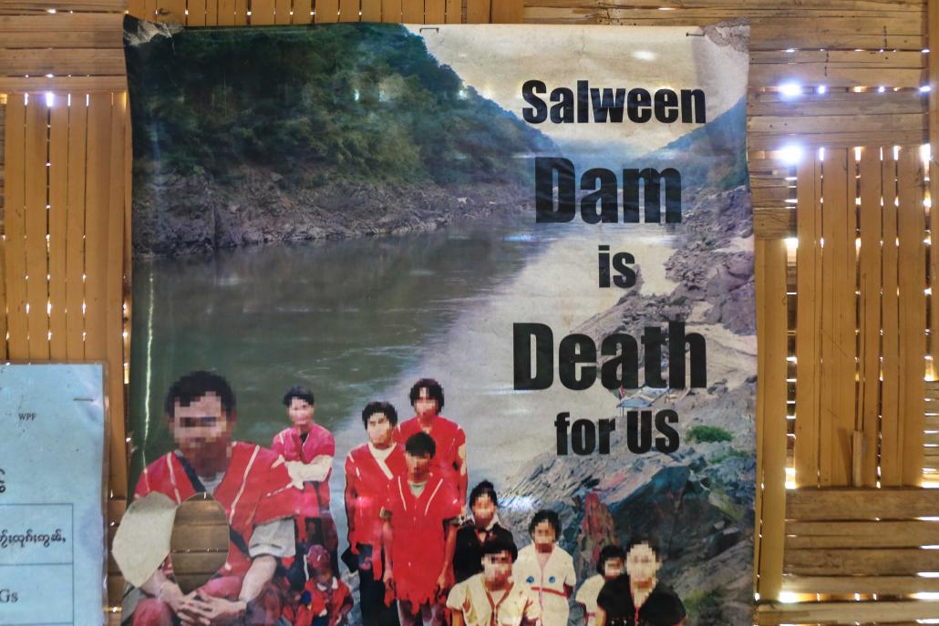 A poster protesting a dam on the Thanlwin River hangs in a meeting room in Loi Kaw Wan camp. Megaprojects like the dam threaten to displace more residents in Shan State. (Victoria Milko | Frontier)