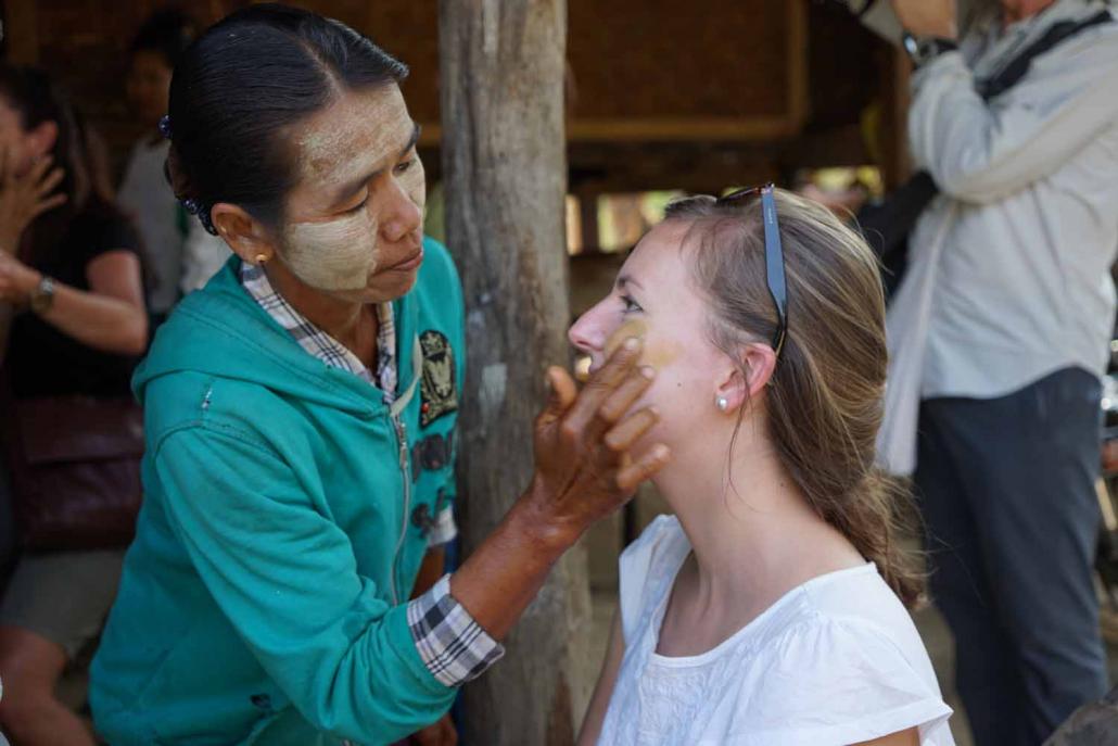 Tourists visit a thanakha plantation in Myaing Township before having some of the tree’s bark paste – a traditional cosmetic – applied to their face. (Supplied)