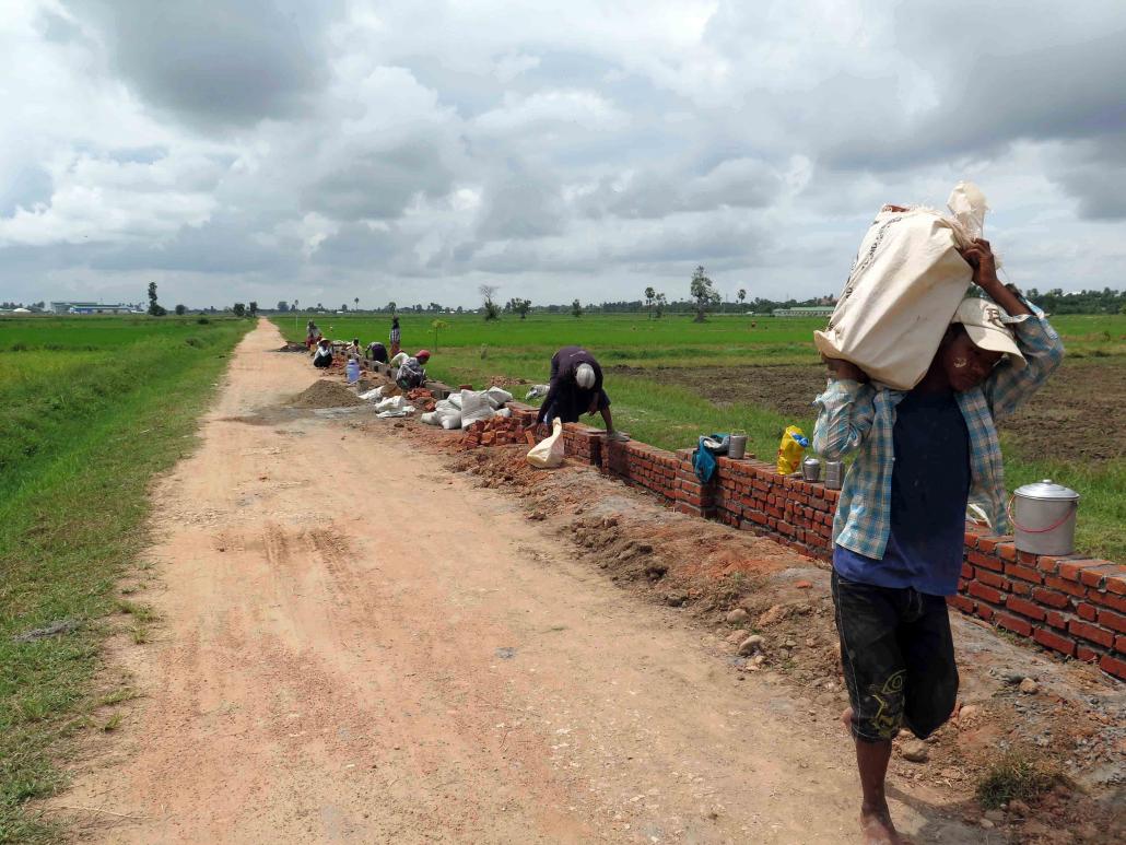Labourers build a wall along the road to the President's Farm in Pobbathiri Township. (Maung Thin Tone / Mawkun)