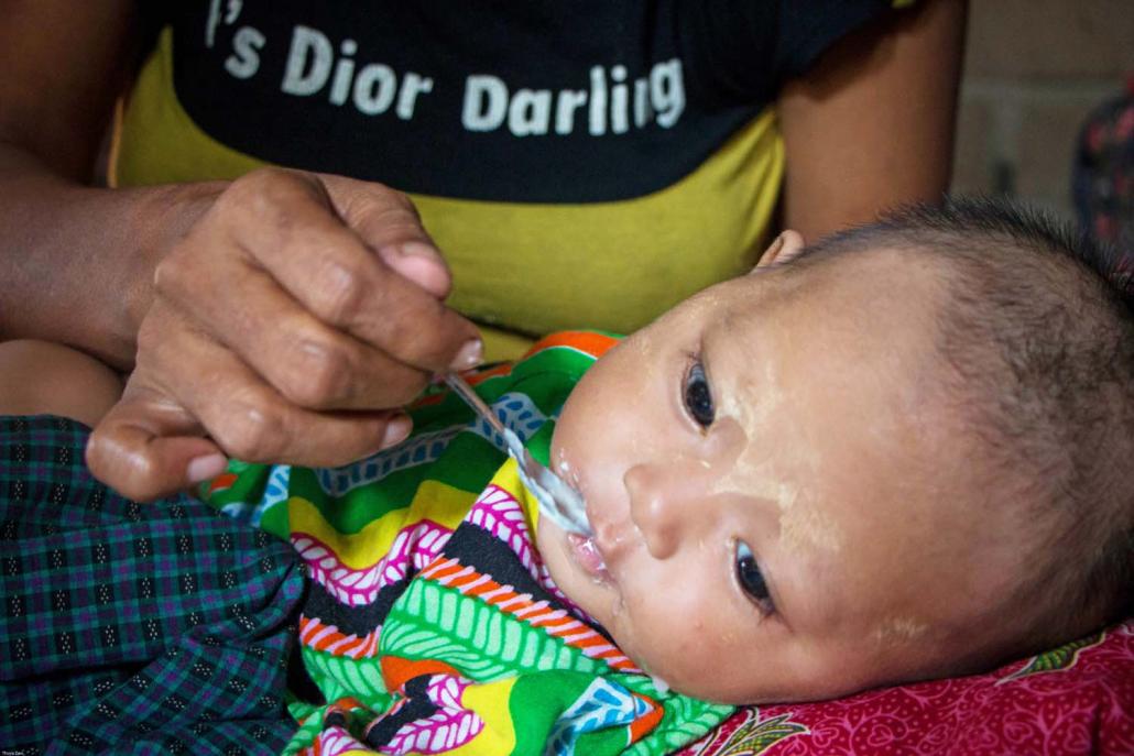 Ma Yu Yu Khaing, a mother of four in Yangon’s South Dagon Township, feeds her two-month-old niece a mixture of rice, water and cheap milk powder. (Thuya Zaw | Frontier)