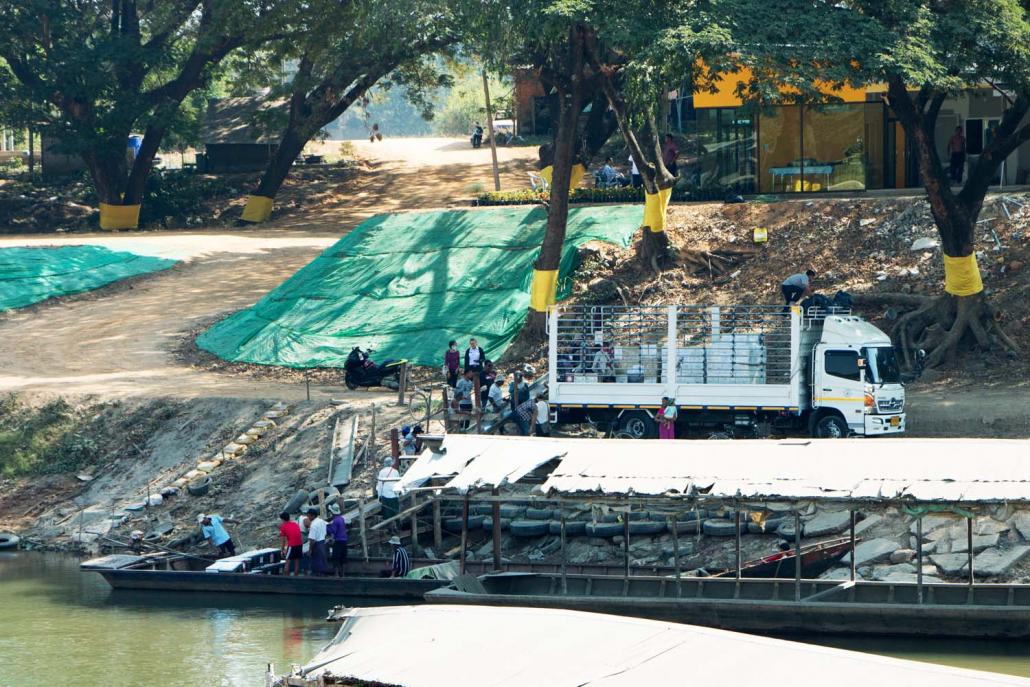 Goods are unloaded from a truck on the Thai side of the Thaung Yin River and loaded onto a small boat. On the opposite bank is an illegal trade gate and warehouse operated by the Kayin State Border Guard Force. (Thuya Zaw | Frontier)