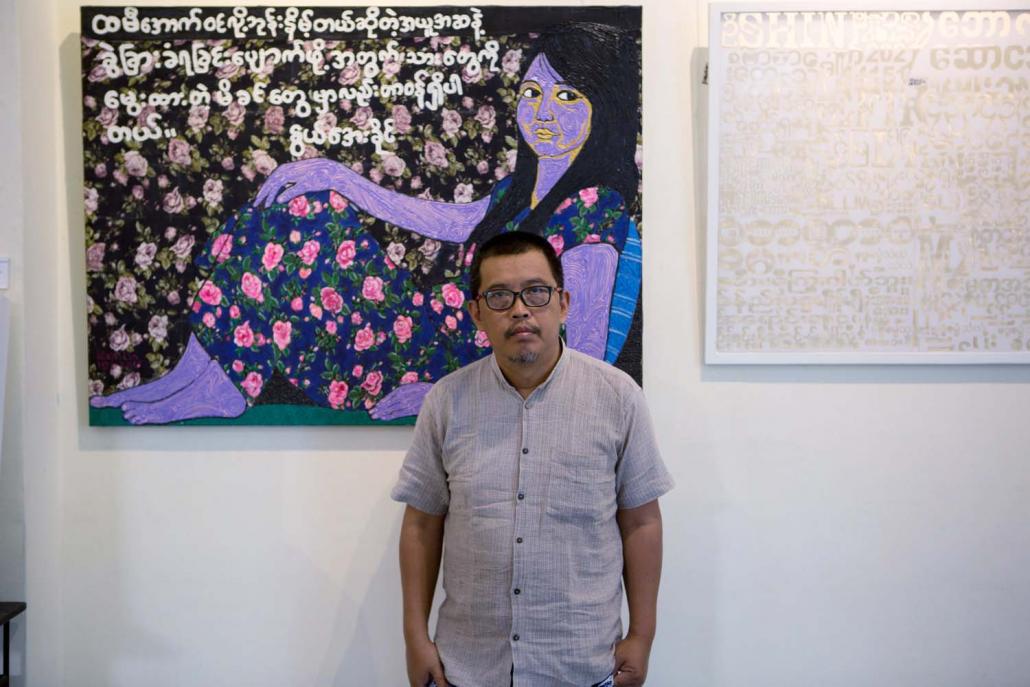 Htein Lin before a painting from his “Skirting the Issue” exhibition, which tackled misogynist taboos with canvases made from women's longyis. (Thuya Zaw | Frontier)