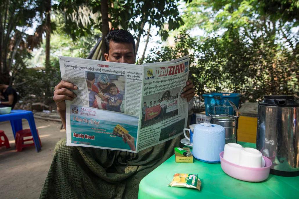 A man reads a copy of the Daily Eleven newspaper at a Yangon teashop. (Teza Hlaing / Frontier)