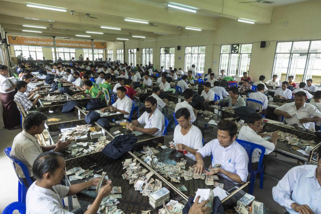 Employees work through piles of small change at the YRTA office in Yangon. (Teza Hlaing | Frontier)