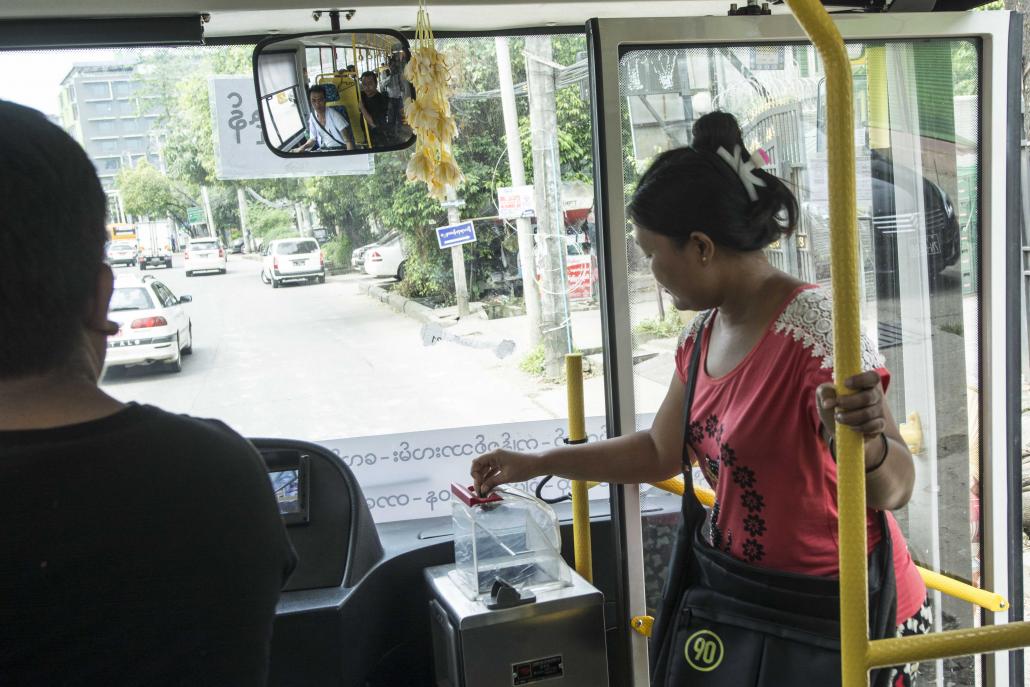 A passenger puts money into a fare box aboard a bus in Yangon. (Teza Hlaing | Frontier)