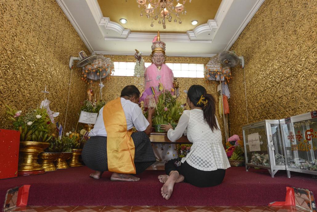 A couple prays at the shrine for Bo Bo Gyi in Yangon's Botahtaung Pagoda. (Teza Hlaing / Frontier)