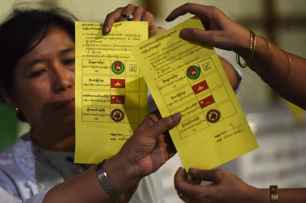 Poll officials display two ballots marked for a USDP candidate during vote-counting in Yangon on November 8, 2015. (AFP)