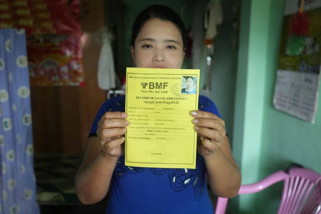 Ma Thandar, 39, who used a microfinance loan from BMF to rent an apartment in Tarmwe Township for her family, shows her loan registration card. (Victoria Milko / Frontier)