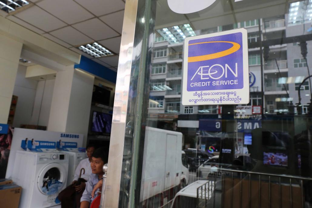 An AEON Credit Service is advertised on the window of a shop in Yangon. (Victoria Milko / Frontier)