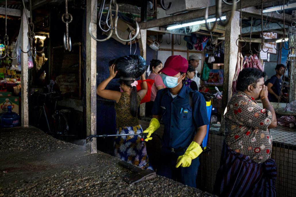 A member of Yangon City Development Committee disinfects Pazundaung market on March 21 as part of efforts to prevent the spread of COVID-19 in Yangon. (Hkun Lat I Frontier)