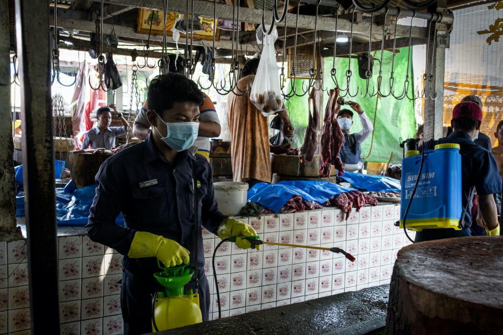 A Yangon City Development Committee official disinfects Pazundaung market to help prevent the spread of COVID-19 in Yangon on March 21. (Hkun Lat I Frontier)