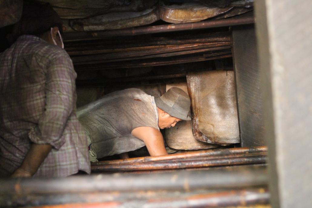 Workers inside a rubber smoke house at the Yadanarpon factory in Thanbyuzayat, Mon State. (Thomas Kean | Frontier)