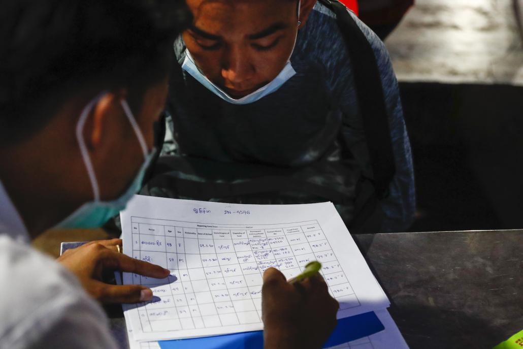 Health workers record the personal information of passengers arriving at Aung Mingalar bus station in Yangon on the night of March 24. (Nyein Su Wai Kyaw Soe | Frontier)