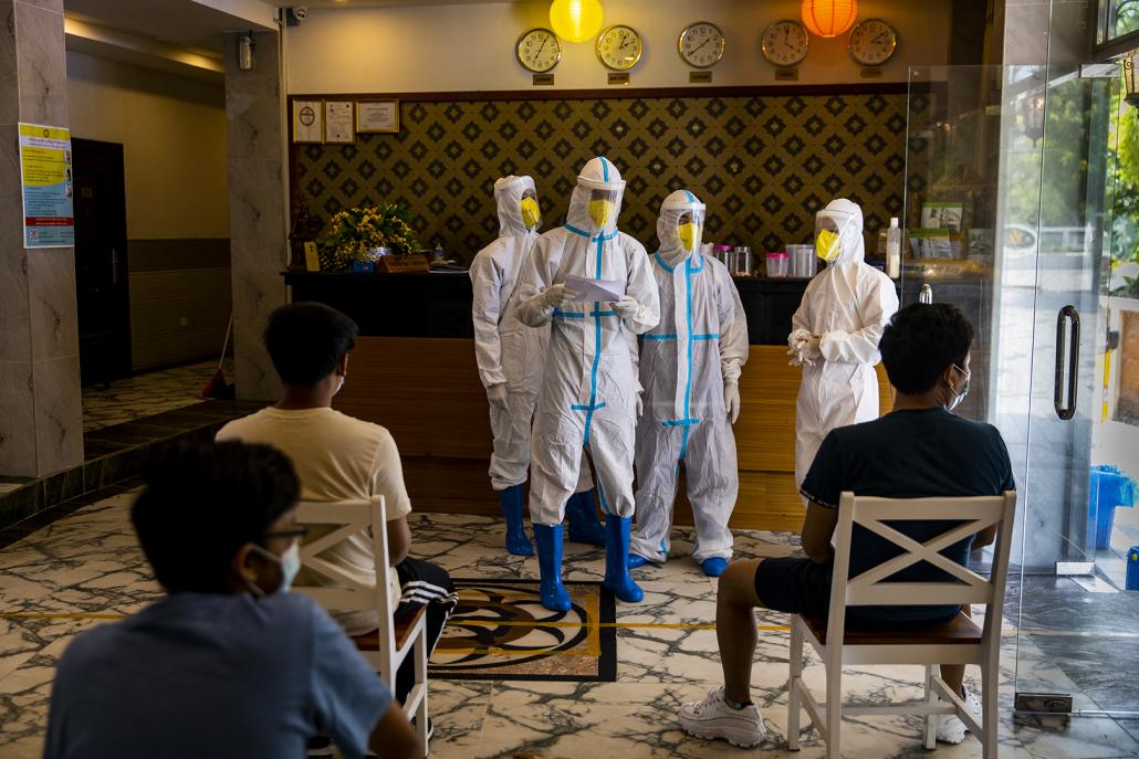 Volunteers and hotel workers check a list of names of people in quarantine who are to be tested for COVID-19 on May 22. (Hkun Lat | Frontier)