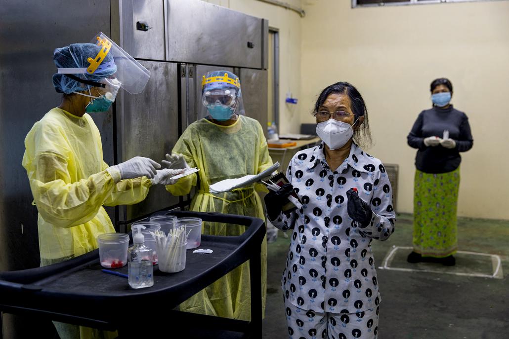 A woman, testing kit in hand, lines up to be tested for COVID-19 at a "quarantine hotel" in Yangon on May 22. (Hkun Lat | Frontier)