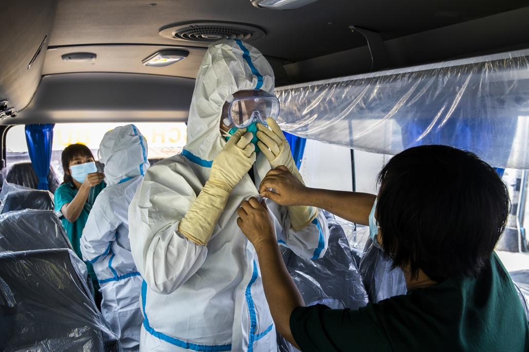 Medical workers put on personal protective equipment before testing for COVID-19 among guests at a "quarantine hotel" in Yangon May 22. (Hkun Lat | Frontier)