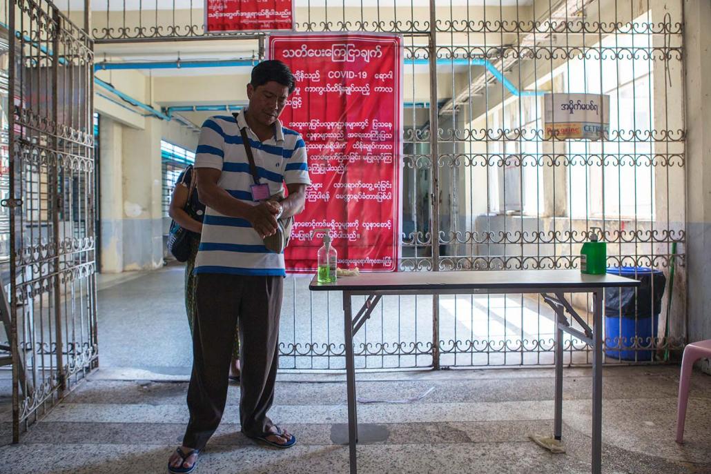A visitor to Insein General Hospital sanitises his hands before entering the building on March 26. (Thuya Zaw | Frontier)