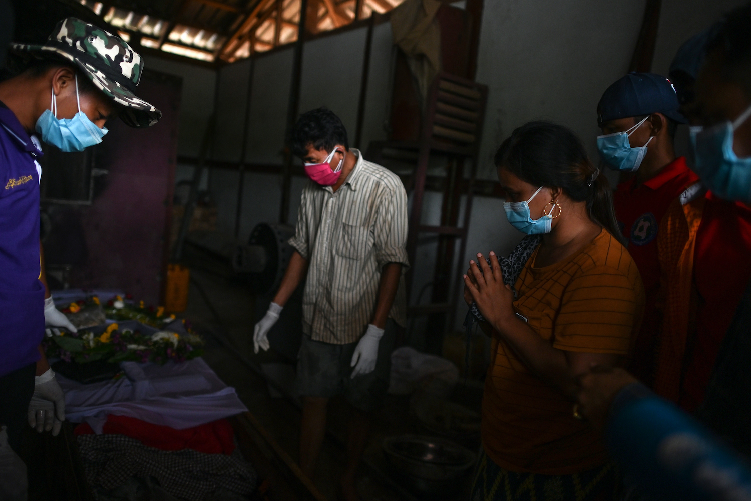 Ma Htar Htar Myint (second right) prays by the coffin of her husband Ko Than Naing before his funeral ceremony, following a deadly landslide in an area of open-cast jade mines, near Hpakant in Kachin State. (AFP)