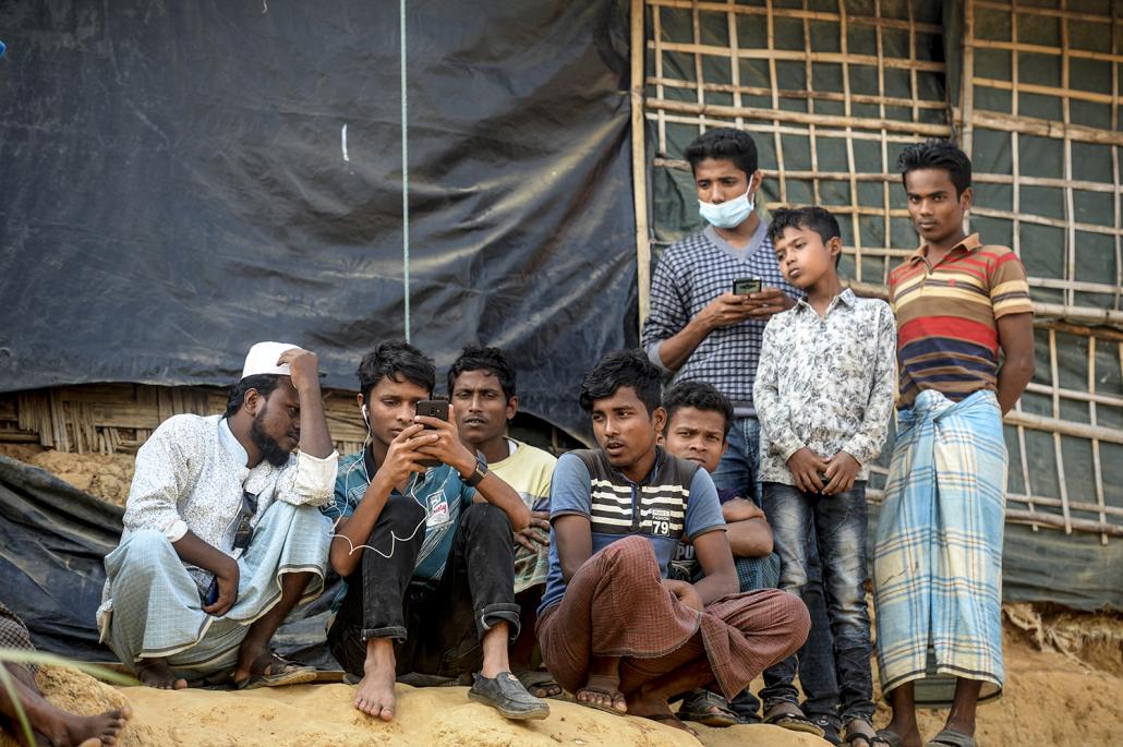 Rohingya refugees watch on a mobile phone a live feed of State Counsellor Aung San Suu Kyi's appearance at the UN's International Court of Justice, in a refugee camp in Cox's Bazar, Bangladesh. (AFP)