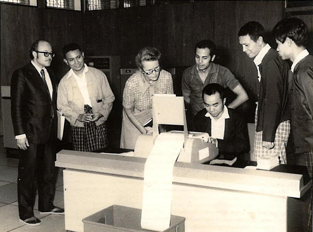 A computer operator uses the ICL 1902S as a visiting United Nations official watches on. (Supplied)