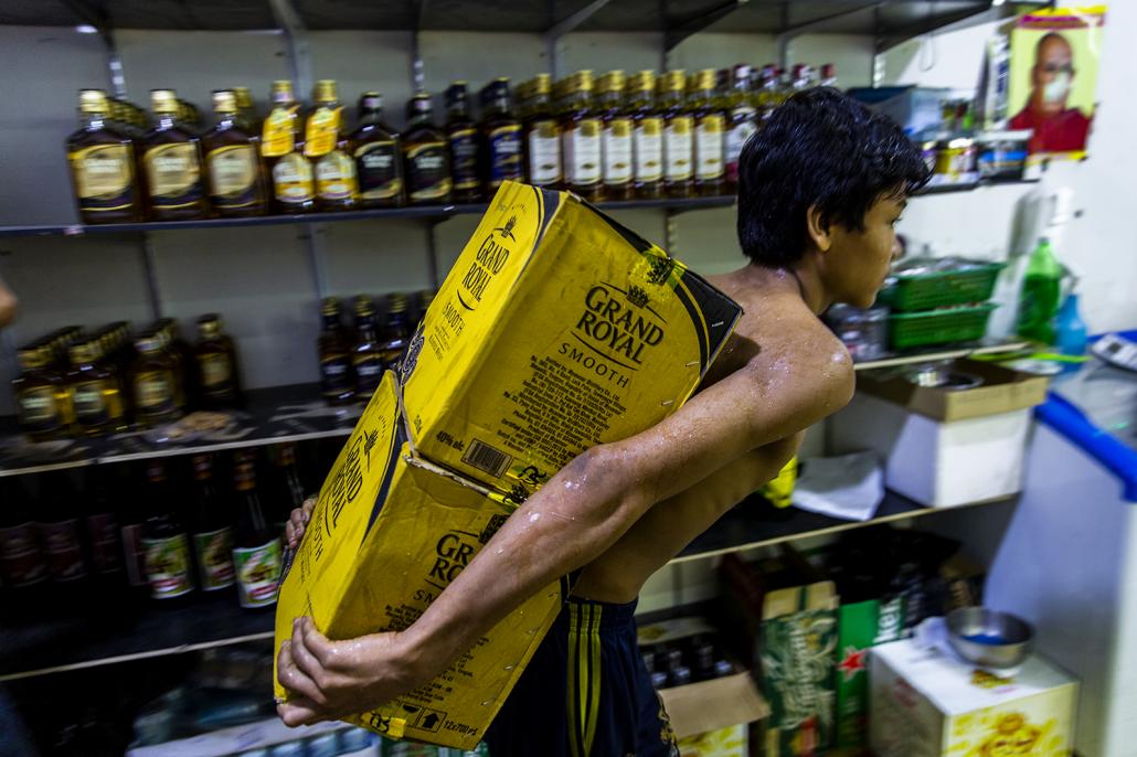 A worker carries boxes of Grand Royal at a liquor shop in Yangon’s Dawbon Township. Owner U Htin Kyaw Aye says that since April he has been unable to order shipments of Thai-made energy drinks and beer from traders in Myawaddy. (Hkun Lat | Frontier)