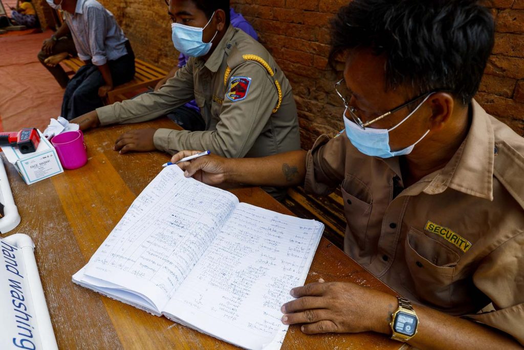 Security guards at the Dhammayangyi temple log the details of visitors undergoing health checks on June 22. (Nyein Su Wai Kyaw Soe | Frontier)