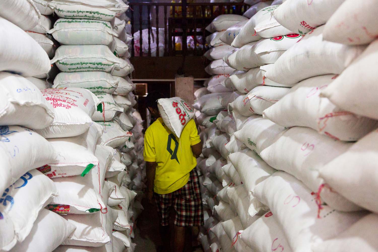 A worker carries a bag of rice inside a warehouse in Insein Township in June 2020. (Frontier)