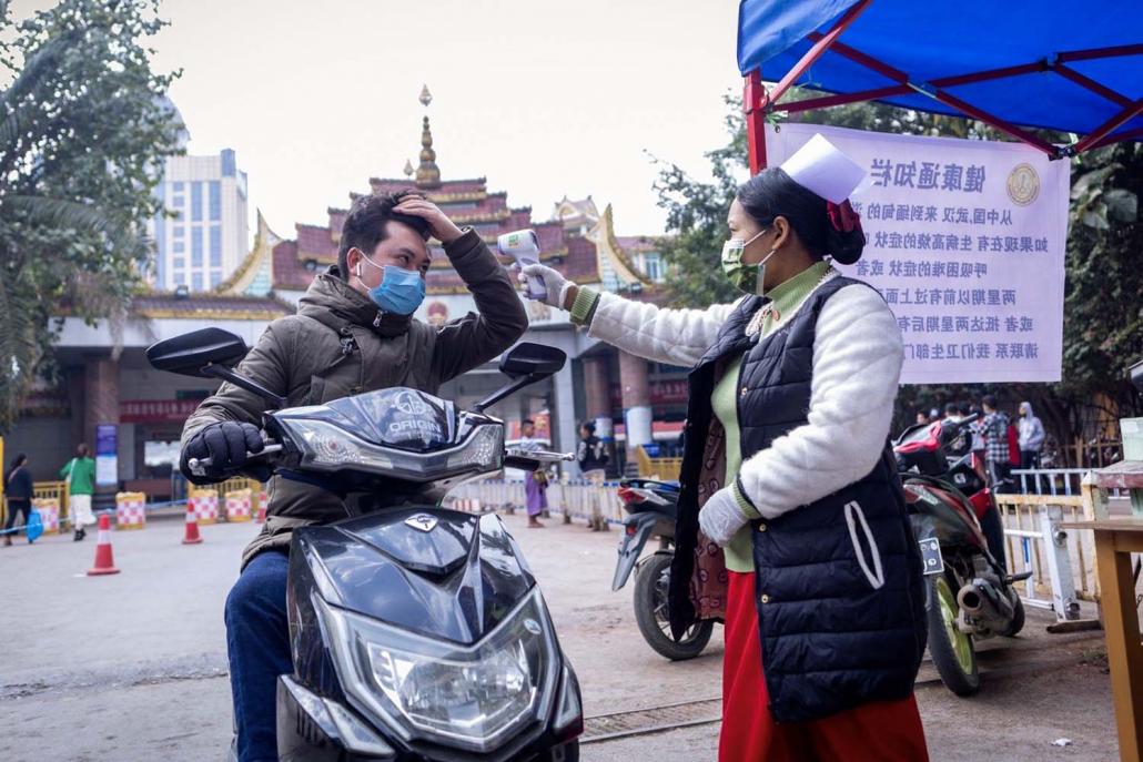 A Myanmar health officer checks the temperature of a motorist entering Myanmar at Muse on January 31. (AFP)