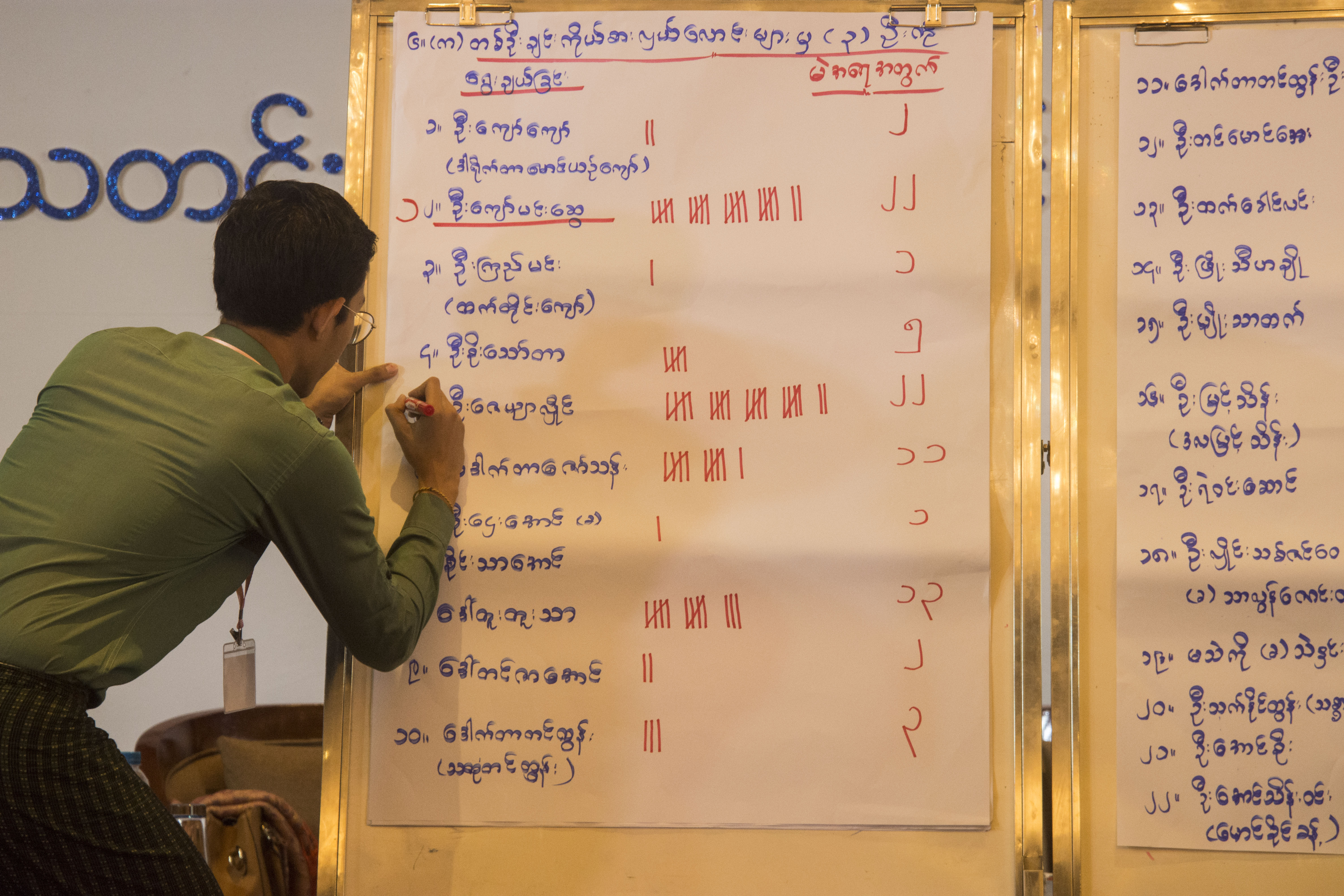 Health workers record the personal information of passengers arriving at Aung Mingalar bus station in Yangon on the night of March 24. (Nyein Su Wai Kyaw Soe | Frontier)