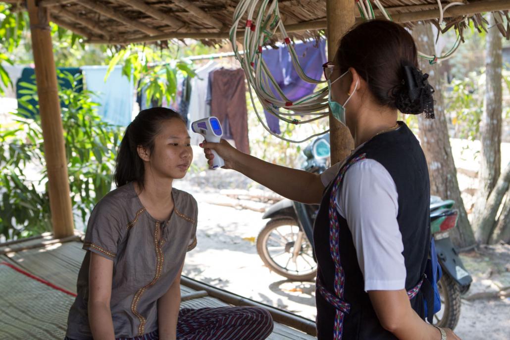 A woman who works in a garment factory in Yangon’s Hlaing Tharyar Township has her temperature checked while quarantining at home in Phya Tha Dike. (Thuya Zaw | Frontier)