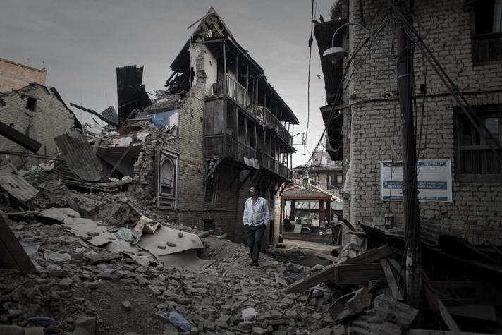 A pedestrian walks past destroyed houses in the village of Satungal on the outskirts of Kathmandu in May 2015. (Philippe Lopez / AFP)