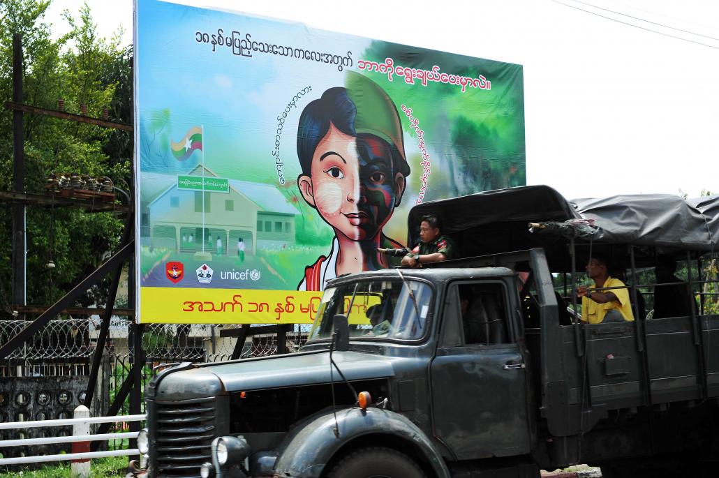 A Tatmadaw truck passes by a public sign stating that only people aged 18 or above can enlist in the military. (Steve Tickner | Frontier)