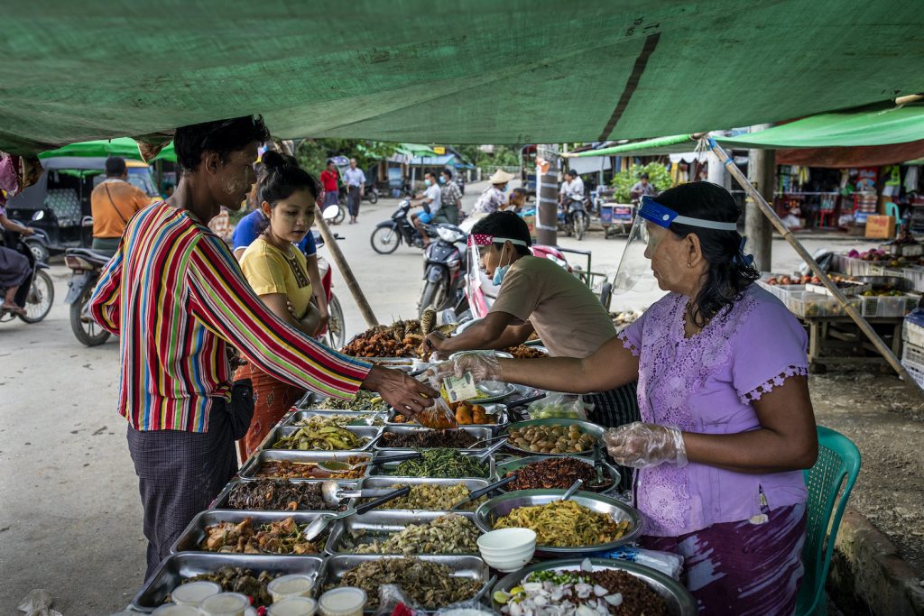 Food vendors wear field shields while serving customers in Mrauk-U, a week before the government ordered a state-wide stay-at-home order to prevent the spread of COVID-19. (Hkun Lat | Frontier)