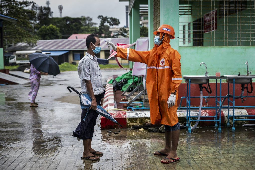 A volunteer checks the temperature of a visitor at the entrance to Sittwe General Hospital in Rakhine State on August 24. (Hkun Lat | Frontier)