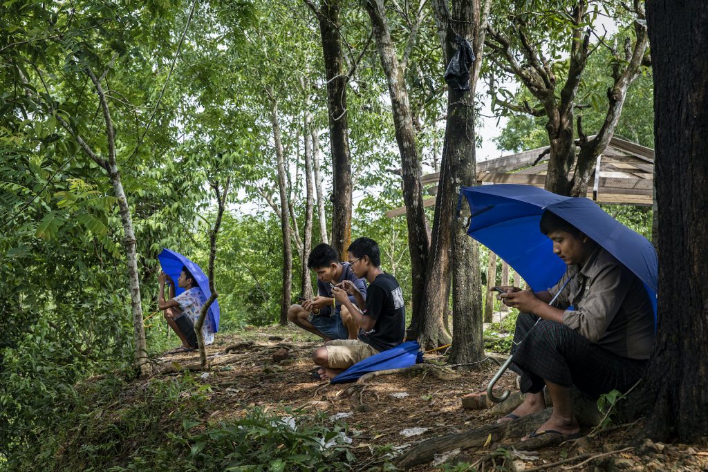 Mrauk-U residents sit atop a forested hill just outside of town trying to get a 3G cell phone signal. Internet has been blocked by the government there for more than year. (Hkun Lat | Frontier)