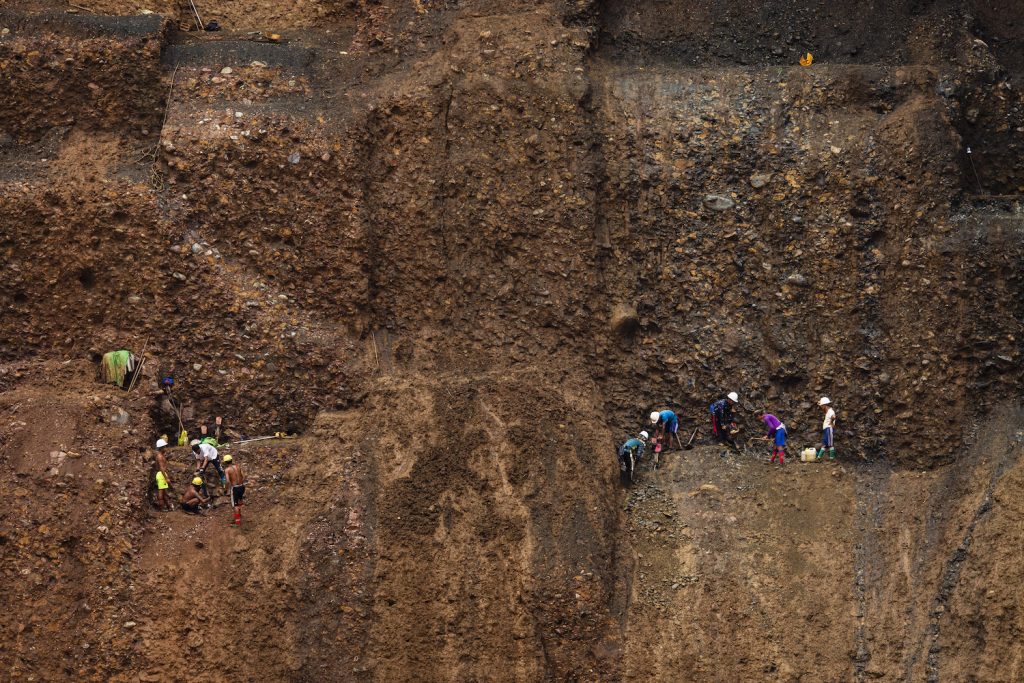 A team of small-scale miners perch precariously on a mine cliffside, using jack hammers to dig for jade on July 15, 2020. (Hkun Lat | Frontier)