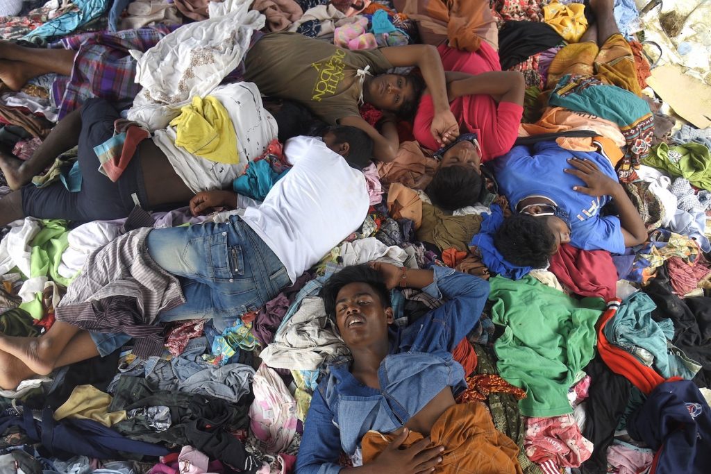 A group of Rohingya men sleep on a pile of donated clothes at a transit camp on September 8, after nearly 300 Rohingya migrants came ashore on the northern coast of Indonesia's Sumatra island. (AFP)