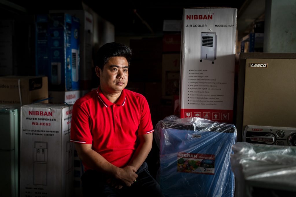 Lum Tu, 33, at his mobile and electronics shop in Myitkyina on July 21. (Hkun Lat)