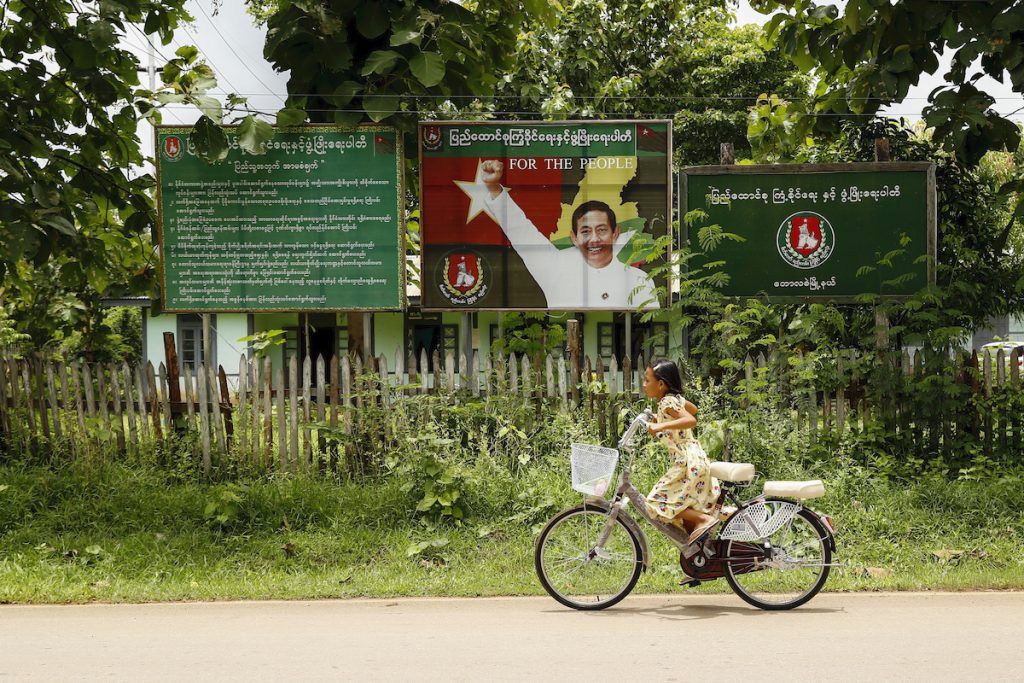 A girl cycles past a USDP campaign billboard in Bawlakhe Township, Kayah State, on August 21. (Nyein Su Wai Kyaw Soe)