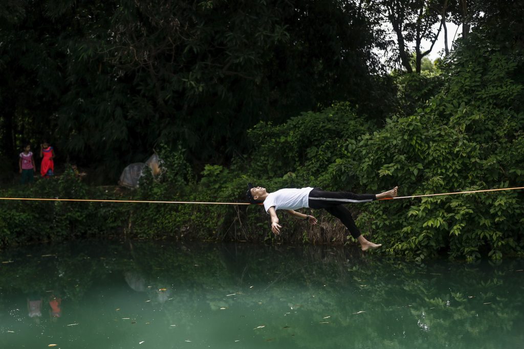 Ko Ye Win Tun balances on a slackline above a pond – what practitioners call "waterlining." (Nyein Su Wai Kyaw Soe | Frontier) 