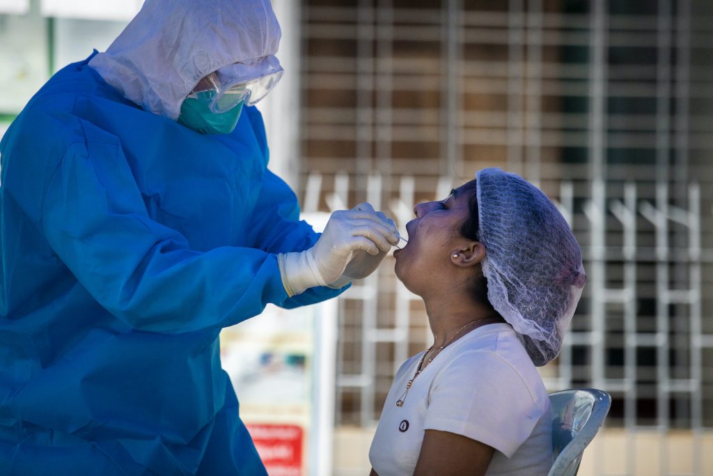 A medical worker takes a sample in downtown Yangon on September 22 from a woman who was quarantined after coming into contact with a COVID-19 patient. (Hkun Lat | Frontier)