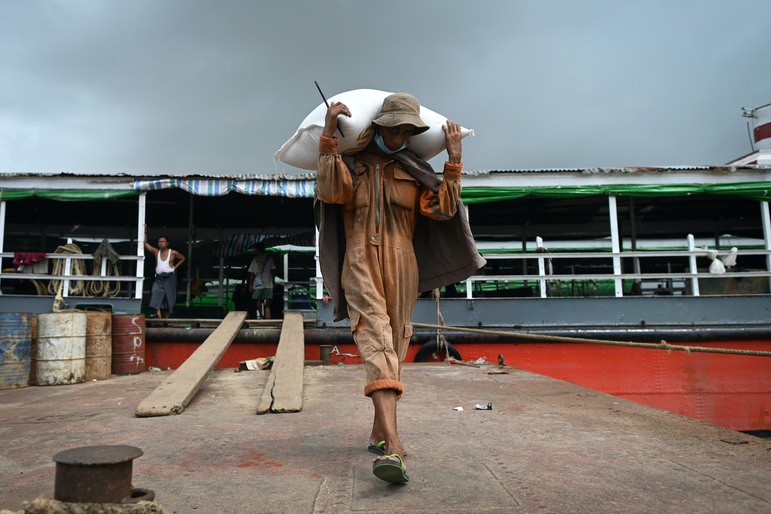 A worker unloads sacks of rice from a boat at the Yangon jetty on July 8. (AFP)