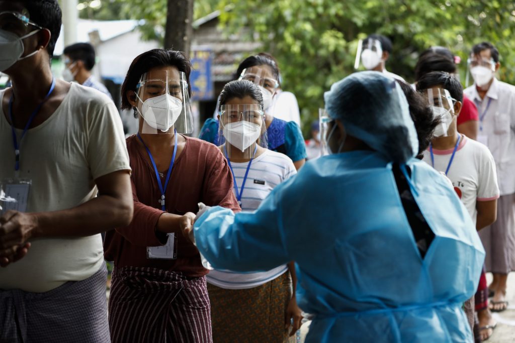 A polling station official hands out sanitiser in Dala's Myo Ma 4 ward. (Nyein Su Wai Kyaw Soe)